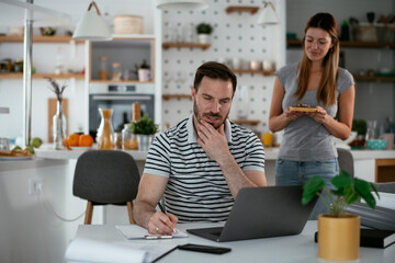 Young woman suprise her husband with cookie. Happy couple enjoying at home..