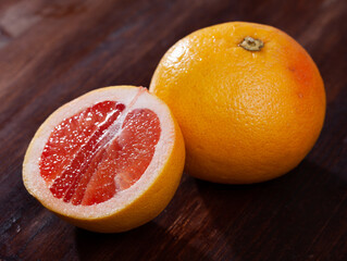 Sliced fresh juicy pink pomelo on wooden table. Concept of health benefits of citrus fruits