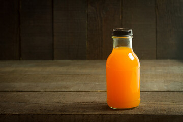 Fresh orange juice in bottle on wooden background.