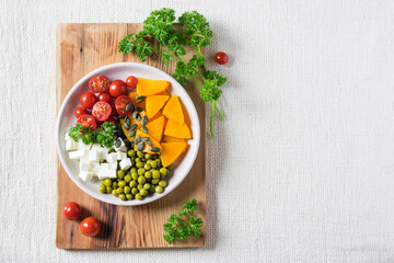 Fototapeta na wymiar Salad with pumpkin, parsley, tomatoes and feta cheese, healthy food for diet. Top view, copyspace