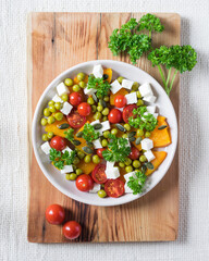 Mixed salad with pumpkin, parsley, tomatoes and feta cheese, healthy food for diet. Top view
