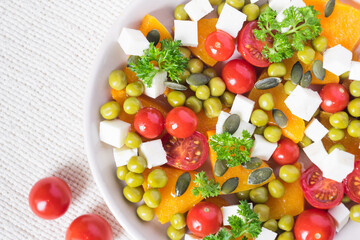 Salad with pumpkin, parsley, tomatoes and feta cheese, healthy food for diet. Top view