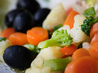 Fish meal served with various vegetables, blurry motion, focus to carrots,