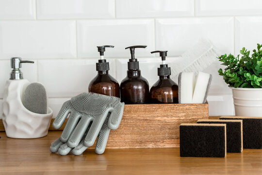 Wooden box with cleaning supplies, gloves, sponges on a modern wooden table. Stylish cleaning kit with copy space for text.