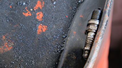 A used spark plug on a used oil collector barrel