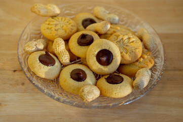 Light brown beige baked peanut cookies filled with dark chocolate, one by one on the plate, tasty Christmas sweets ready to eat
