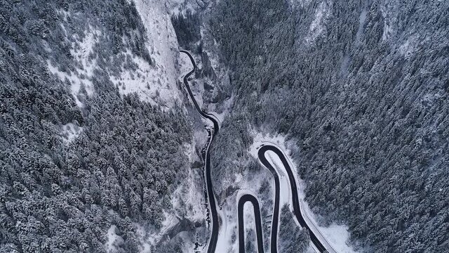 Aerial drone 4K footage of a curved windy road motorway through mountains next to a river in winter landscape in Romania - Bicaz Gorges