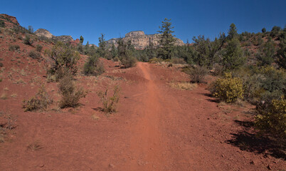 Dusty red dirt trail leading to a rock formation  