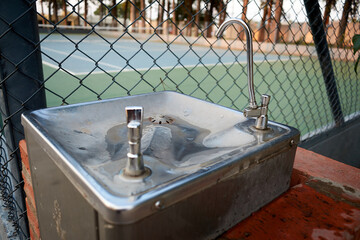 bebedero de agua. cancha de tenis. malla metálica, parque, agua, deporte