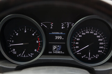 The dashboard of the car is glowing white with arrows at night with a speedometer, charge battery level and volume of oil in the engine to monitor the condition in modern style on black isolated.