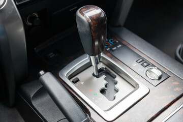 Fototapeta na wymiar The automatic transmission gear knob in the car interior is gray with a wood-look panel insert for driving and acceleration. Dealer warranty and recall of transmission.