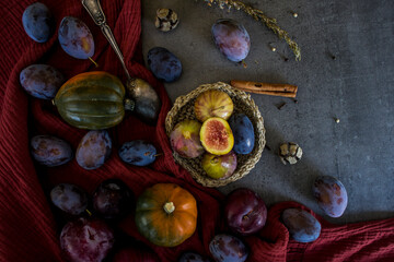 Fototapeta na wymiar Fresh fruits and vegetables on a table: plums, grapes, pumpkin and figs. Autumn mood still life. 