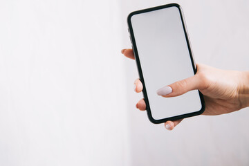 phone with a white screen in the hands of a girl with a manicure, copy space