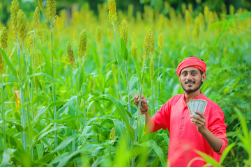 indian farmer counting and showing indian rupees at sorghum field