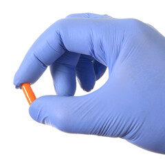 Hand in latex medical glove holding capsule drugs