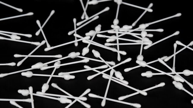 Cosmetic cotton swabs are scattered on a black background. 4K video