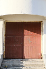 An old abandoned warehouse, a brown gate with peeling paint on a light background. Light background of the wall. Rustic style.