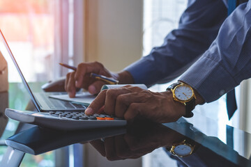 Business man hand using calculator and sign cheque.