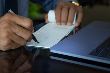 Business man hand sign cheque book.