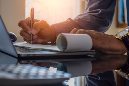 Business man hand sign cheque book with laptop computer on the desk.