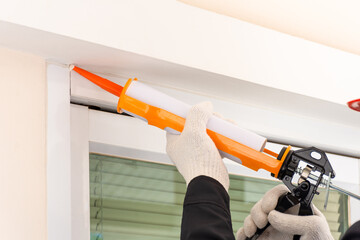 Technician man hand using glue gun, silicone tube or manual caulking gun 