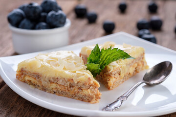 Two pieces of almond cake on a white plate and blueberries