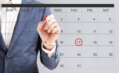 Unrecognizable businessman hand marking dates with red marker on virtual calendar
