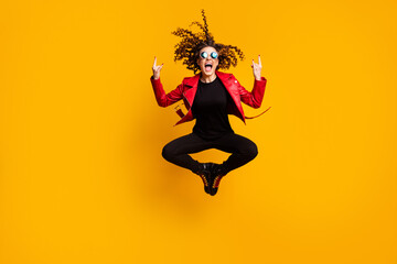 Fototapeta na wymiar Full length body size view of cool crazy cheery wavy-haired girl jumping showing horn sign having fun isolated on bright yellow color background