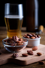 A glass of beer and smoked salted nuts on a wooden background. Beer snack.