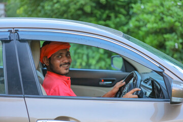 Happy young indian farmer driving new car