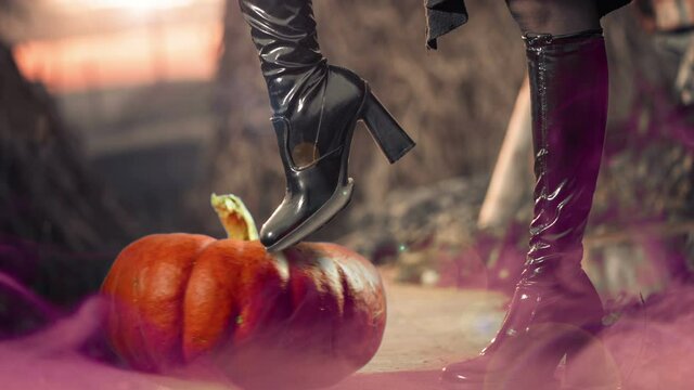 woman in blak clothes holding leg over spinning halloween pumpkin