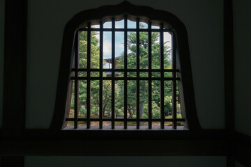 Looking at the architecture and gardens of Tenryuji Temple through an old wood window