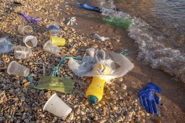 Plastic debris and face masks on the beach. Coronavirus COVID 19 is contributing to pollution, as...
