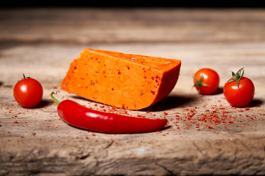 Red gourmet cheese with tomatos and parika on rough wooden planks