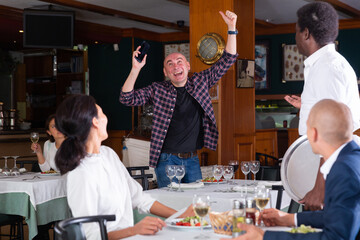 Portrait of excited man talking on mobile phone and screaming with happiness from good news in restaurant
