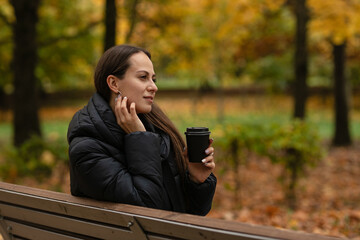 a girl in the Park in autumn drinks coffee and enjoys nature