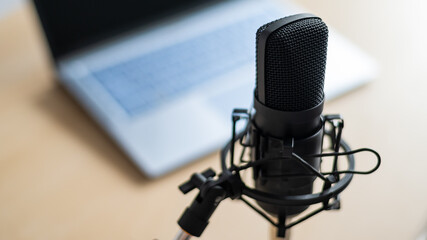 Close-up of a professional microphone on the background of a laptop. Radio broadcaster's desktop