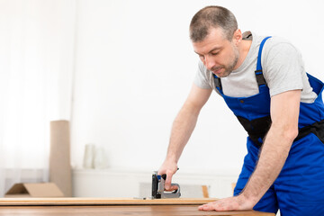 Professional Carpenter Working Using Staple Gun Making Furniture Standing Indoors
