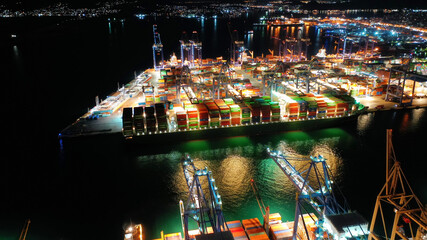 Aerial drone night shot of illuminated container terminal facilities in popular Mediterranean...