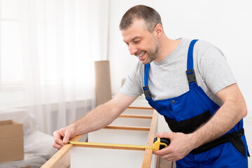 Cheerful Furniture Assembler Measuring Shelf With Tape Standing Indoor