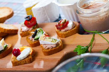 Assorted homemade crostini appetizers with different filling served on wooden cutting board