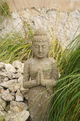 Close-up of a stone statue of a Buddhist woman meditating among the plants
