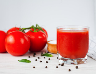 Glass of fresh tomato juice, ripe tomatoes and salt on a white background. Close-up.