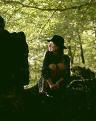 Trendy girl in the woods wearing a black dress and a fedora hat during autumn in Spain.