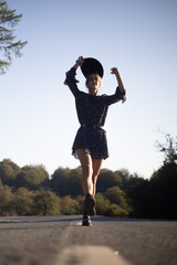 Trendy girl in the woods wearing a black dress and a fedora hat during autumn in Spain.