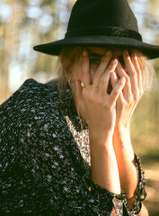 Trendy girl in the woods wearing a black dress and a fedora hat during autumn in Spain.