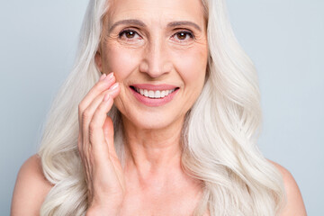 Close up photo of beautiful aged woman grey hair lady applying daily night cream cheek isolated grey color background