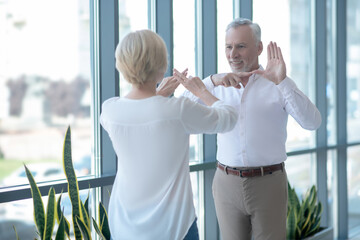 Bearded gray-haired male and blonde female talking using sign language