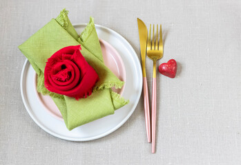 Valentine's Day table setting with linen napkins, fork, knife and heart of chocolate.