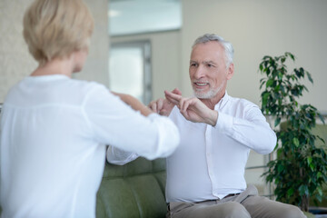 Smiling gray-haired male talking with blonde female using sign language